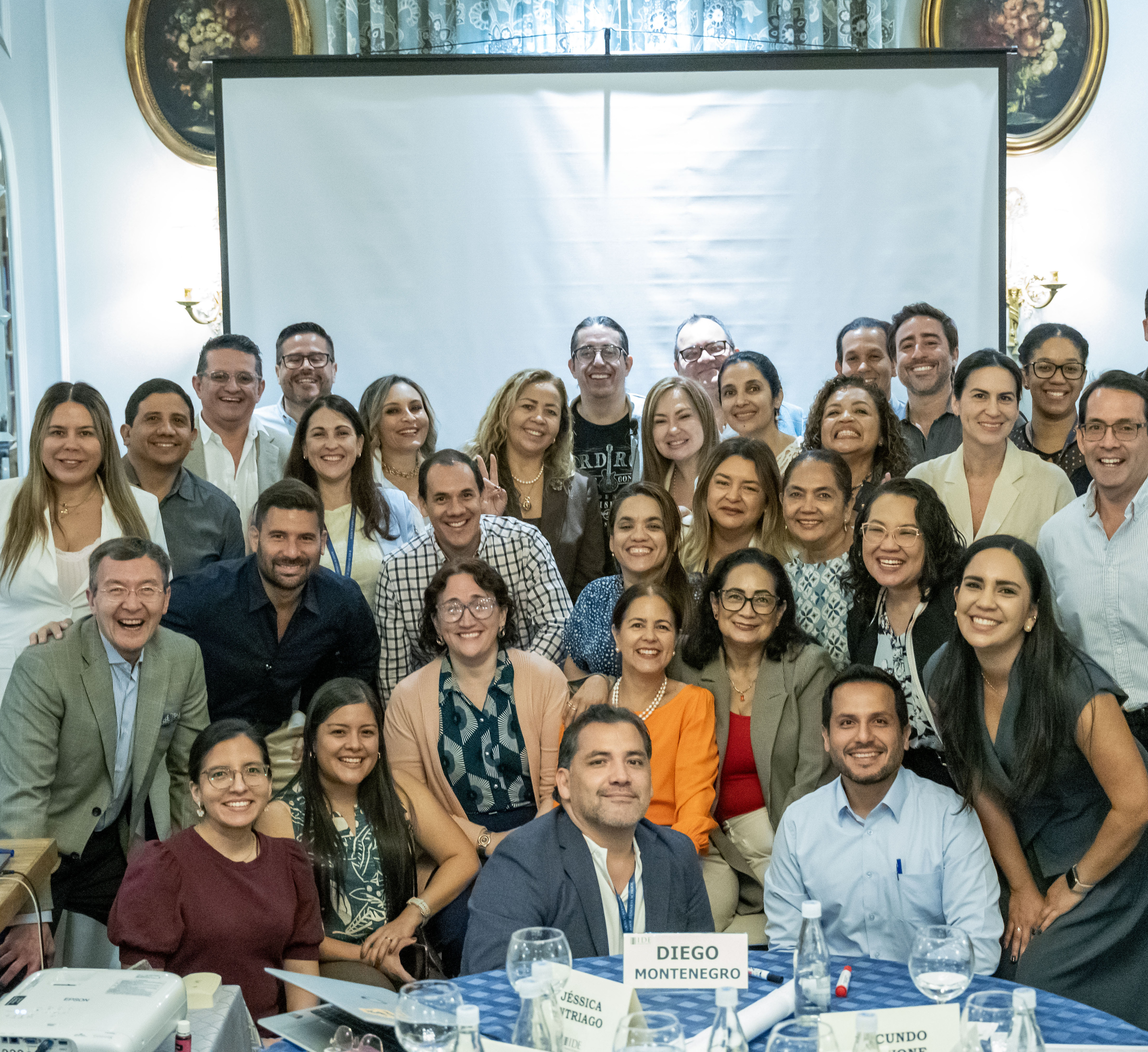 Group of diverse professionals posing for a group photo at a conference table, smiling.